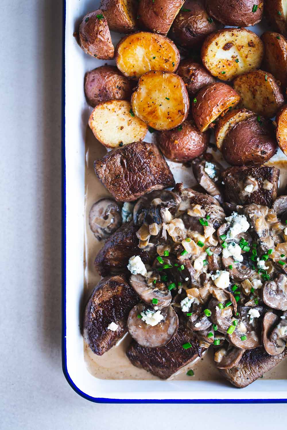 Steak tips, mushrooms, blue cheese sauce and potatoes on a sheet pan