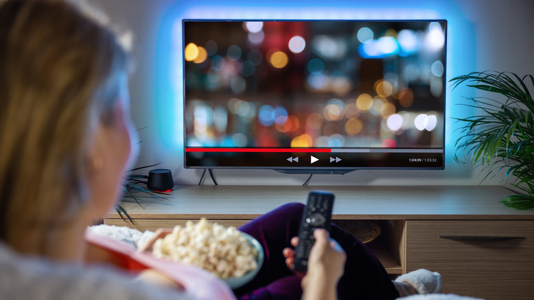 Person watching tv with popcorn and controller in hand
