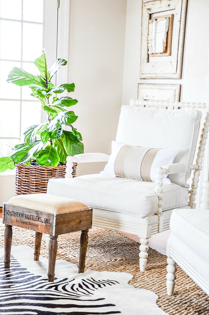 white chair with wooden stool and fiddleleaf fern in basket