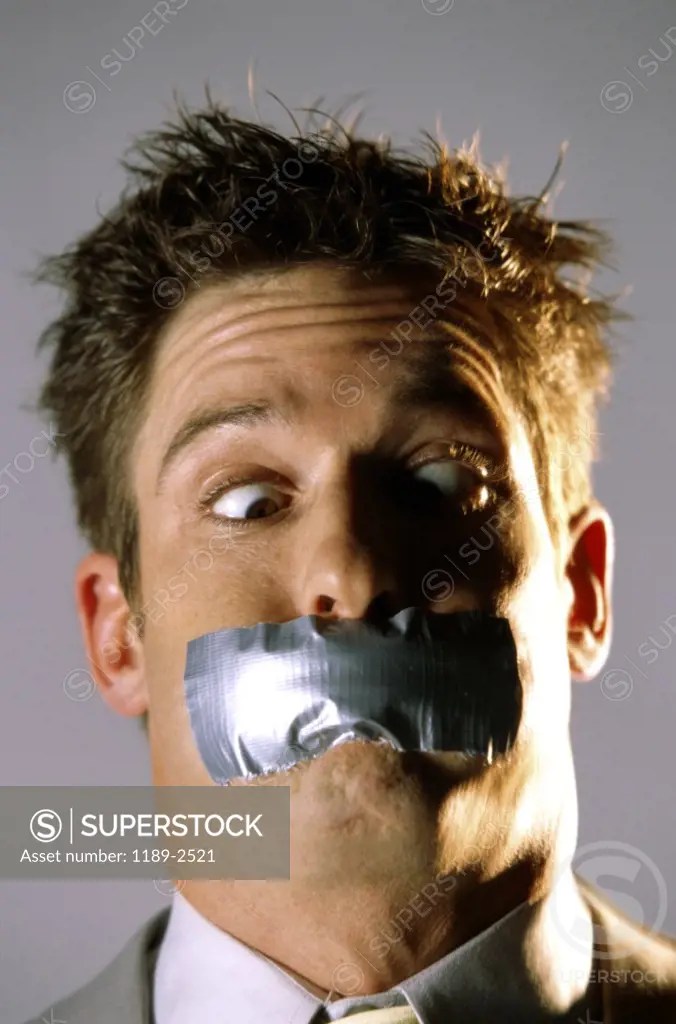 Businessman with tape on his mouth SuperStock