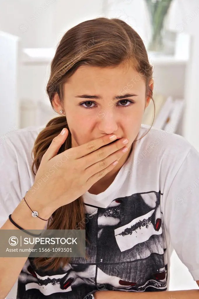 Teenage girl putting her hand in front of her mouth afraid,
