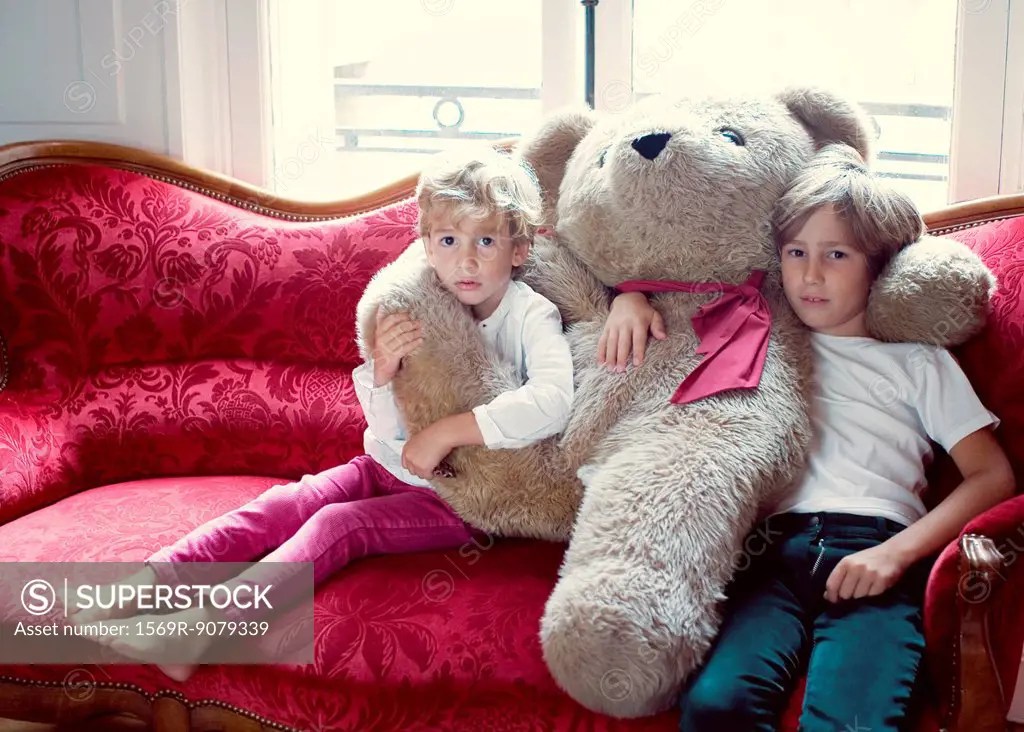 Young brothers embracing large teddy bear, portrait SuperStock