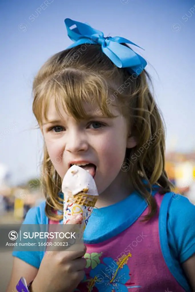 Young girl eating ice cream cone SuperStock