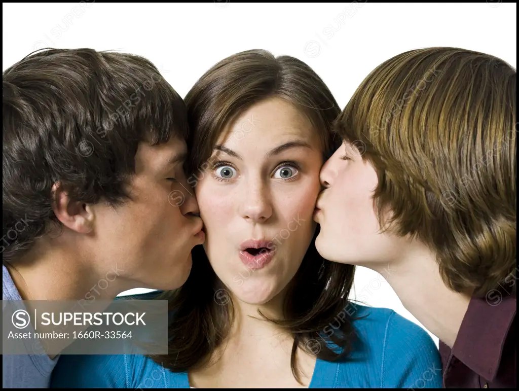 Two boys kissing girl on cheeks SuperStock