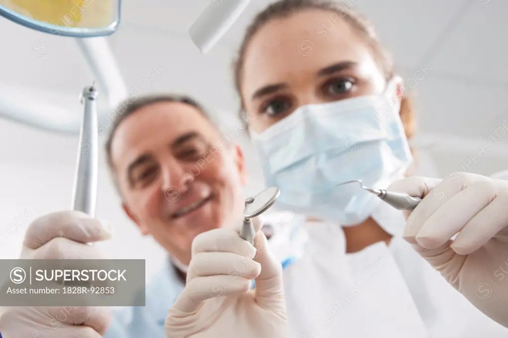 Closeup of Dental Instruments held by Dentist and Hygienist in Dental