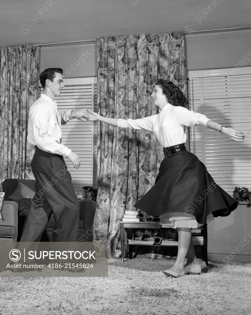 1950s TEEN BOY AND GIRL JITTERBUG DANCING TO ROCK AND ROLL MUSIC IN