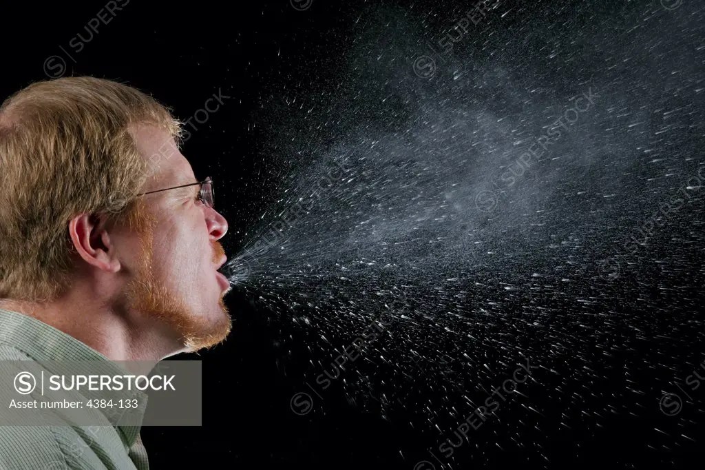 A sneeze in progress, revealing the plume of salivary droplets as they