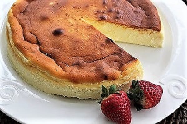 Homemade Ricotta Cheesecake made with ricotta made from scratch Ricotta Cheesecake with Homemade Ricotta on a white cake plate with a slice removed