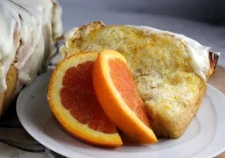 Orange Pull-Apart Coffee Cake slice on a white plate with orange slices.