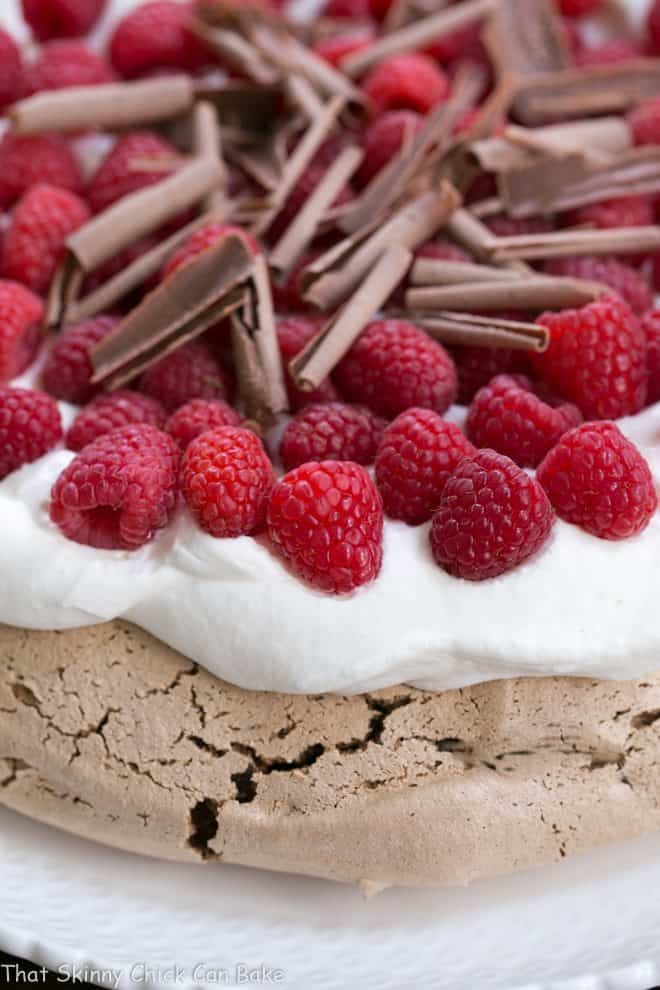 Chocolate Raspberry Pavlova - A sublime dessert with a chocolate meringue topped with berries and cream Edge of a Chocolate Raspberry Pavlova topped with chocolate shavings.