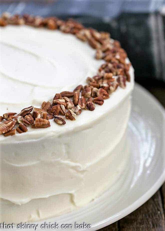 Cheesecake Filled Carrot Cake - Two decadent desserts in one for one showstopper of a cake! Partial view of whole cheesecake stuffed carrot cake with cream cheese frosting.
