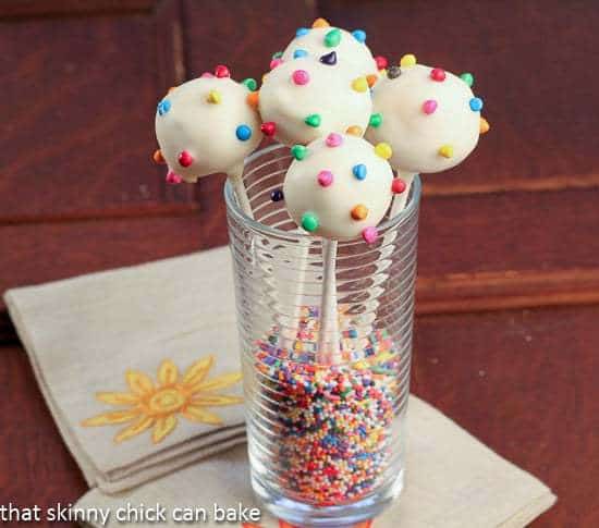 White Chocolate Dipped Cheesecake Pops - an exquisite, bite-sized treat! White Chocolate Dipped Cheesecake Pops in a tall glass
