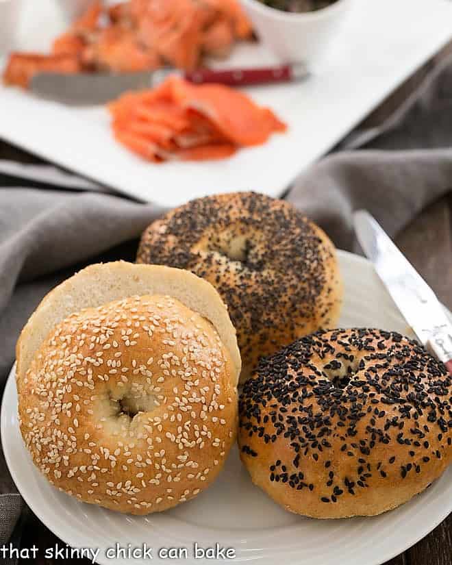 Dense, chewy Homemade Bagels sprinkled with seeds make for a marvelous breakfast or brunch treat. Making bagels from scratch will make you feel like an accomplished baker, plus your house will have a most enchanting aroma Homemade Bagels with a tray of smoked salmon and toppings.