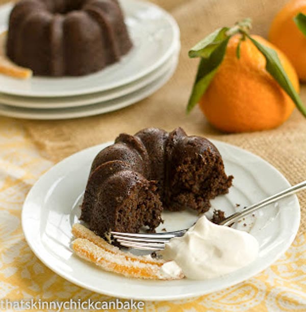Mini Gingerbread Bundt Cakes - Mini holiday cakes garnished with candied orange peel Partially eaten Gingerbread Baby Cake on a white plate with whipped cream and a fork