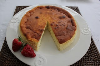 Luscious Ricotta Cheesecake made with homemade ricotta ricotta on a white plate with strawberries and a slice removed