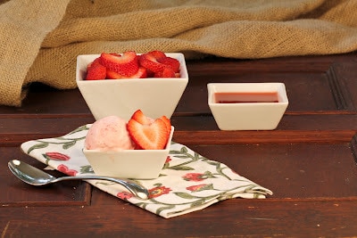 Small white bowl filled with strawberry mascarpone ice cream and fresh strawberry slices