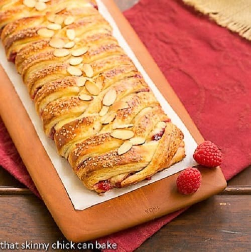 Homemade Raspberry Danish - Tender dough filled with raspberry and cream cheese. Plus how to make a cheater laminated dough! Raspberry Danish Braid on a wooden cutting board.