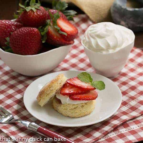Double Strawberry Rose Shortcakes - an elegant, unusual twist to strawberry shortcakes Double strawberry rose shortcake on a white plate next to bowls of strawberries and cream.