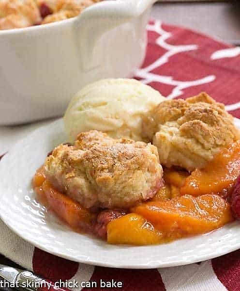 Peach Raspberry Cobbler - Sweetened fresh fruit dessert with a biscuit topping! Peach Raspberry Cobbler on a white dessert plate with a scoop of vanilla ice cream.