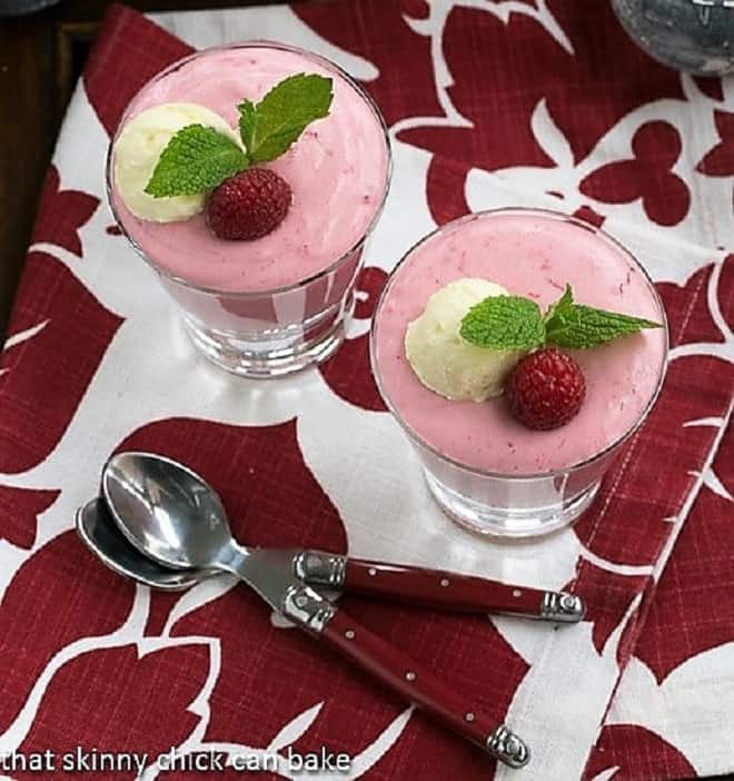 Raspberry Mousse - a light luscious dessert made with frozen raspberries and cream Raspberry Mousse in highball glasses viewed from above with red handled spoons over a red and white napkin