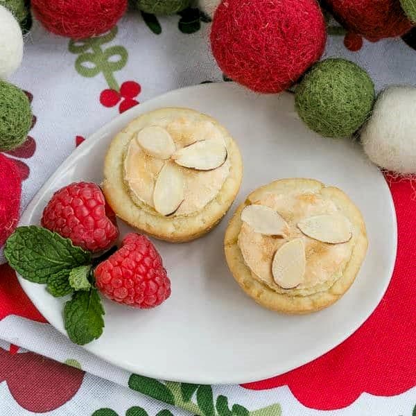 Almond Raspberry Tartlets - Raspberry jam and almond paste fill cream cheese pastry tartlets Overhead view of Almond Raspberry Tartlets on an oval white plate.