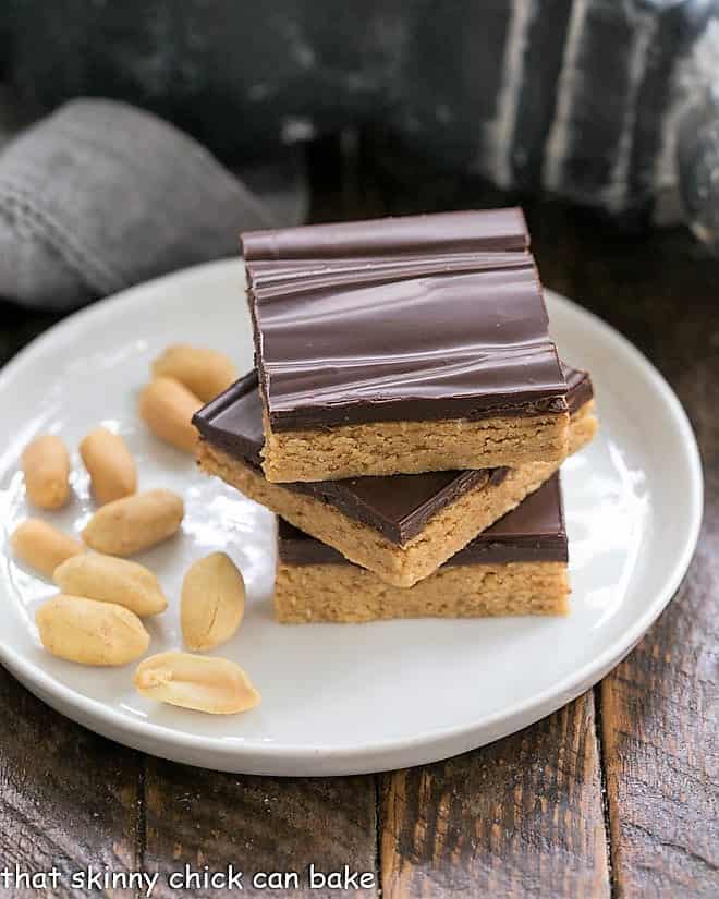 Homemade Reese's Bars - All the magnificent flavors of a Reese's peanut butter cup in a no-bake bar Homemade Reese's Bars stacked on a roung plate with shelled peanuts.
