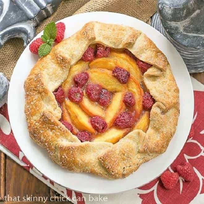Peach Raspberry Galette - A rustic tart that's so much easier to make than pie! Overhead view of aPeach Raspberry Galette on a white ceramic cake stand.