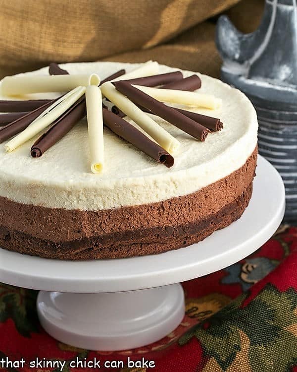 Layered Mousse Cake is an exquisite triple-layered mousse cake that's perfect for the chocoholics in your life! An elegant dessert recipe! Layered Mousse Cake on a cake stand.