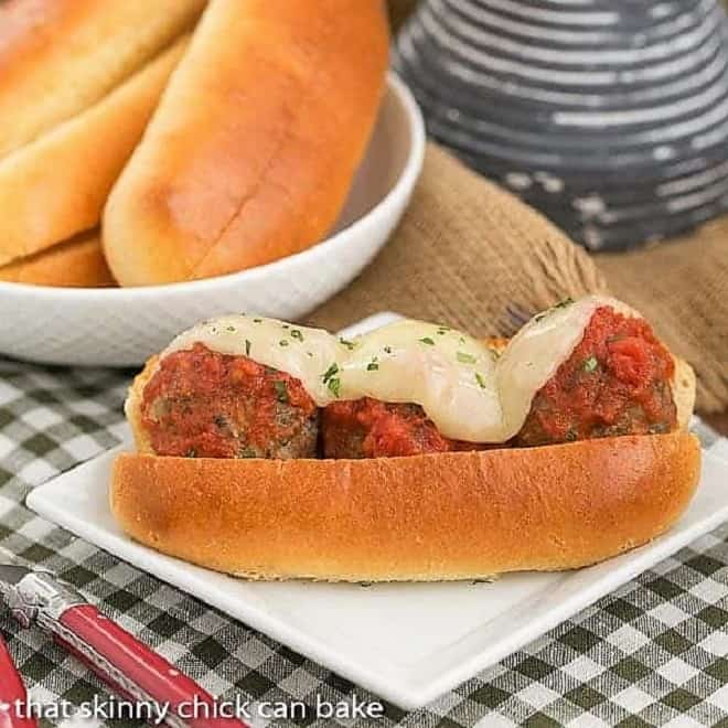 Easy Italian Meatball Subs - A marvelous sandwich filled with plump meatballs, marinara and melted Provolone Easy Italian Meatball Subs on a white square plate on a checked napkin.