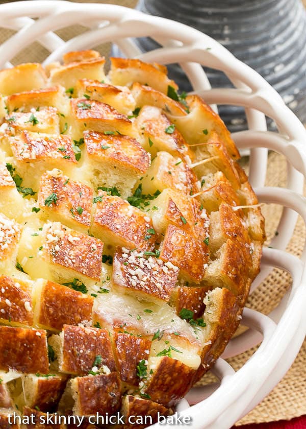 Cheesy Garlic Bread - A crosshatch cut loaf full of melty cheese and garlic! Close up view of Cheesy Garlic Bread in a white ceramic basket.