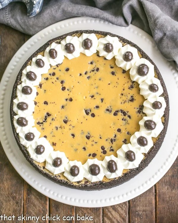 Mocha Cheesecake with Chocolate Chips - Luscious coffee flavored cheesecake speckled with mini chocolate chips! Overhead view of Mocha Cheesecake with Chocolate Chips on a white cake plate