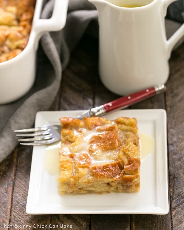 Cinnamon Bread Pudding with Whiskey Sauce - An unusual tweak makes this the lightest, tenderest, most amazing bread pudding! Slice of Cinnamon Bread Pudding with Whiskey Sauce on a square white plate.