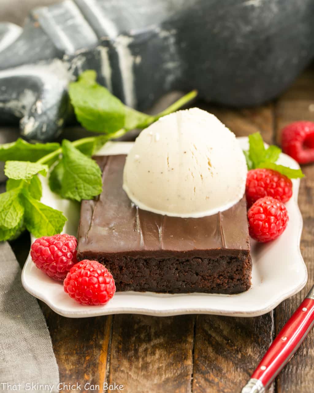 Fudgy Chocolate Sheet Cake with Cocoa Icing - A delectable, ultra-chocolate dessert that feeds a crowd! #sheetcake #chocolate Ice cream topped Fudgy Chocolate Sheet Cake with Cocoa Icing on a white dessert plate.