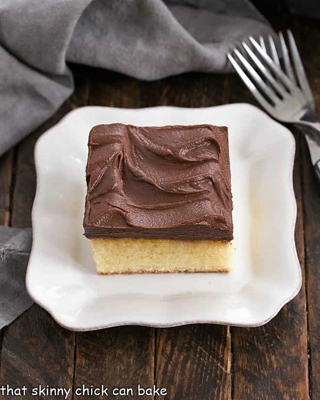 Overhead shot of a square of yellow snack cake on a square white dessert plate.