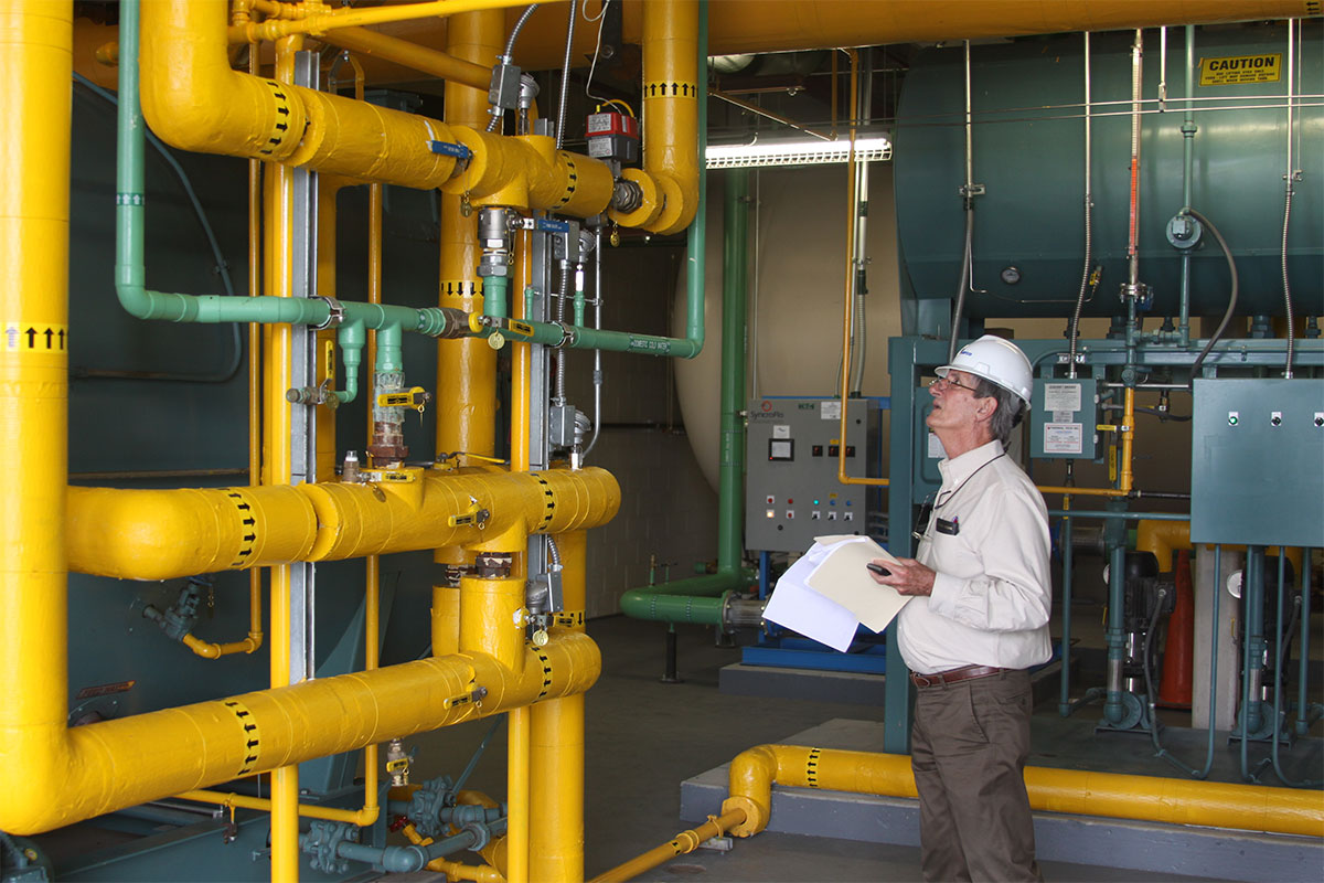 Worker checking on big yellow pipes Thermal Tech