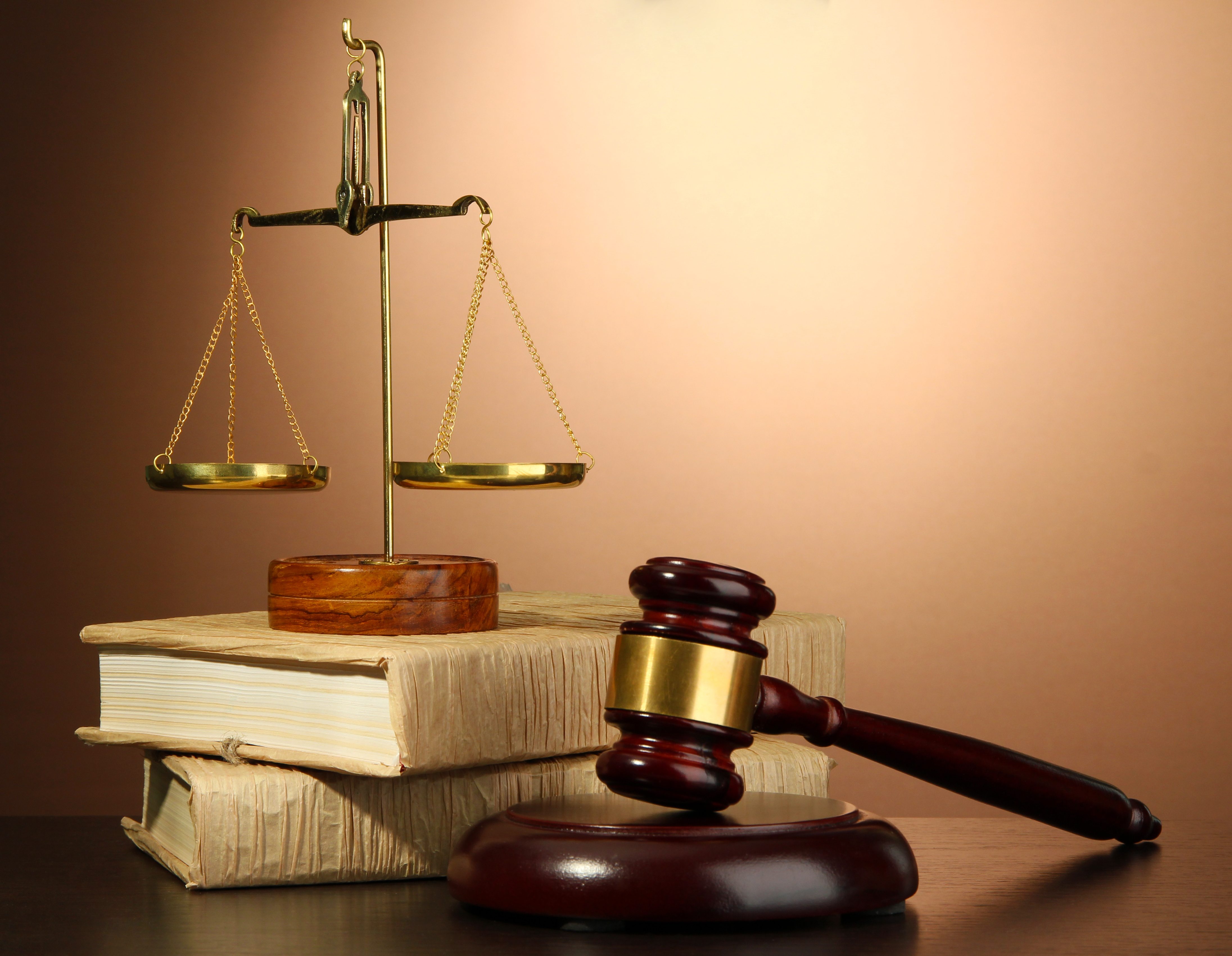 Golden scales of justice, gavel and books on brown background Tracy