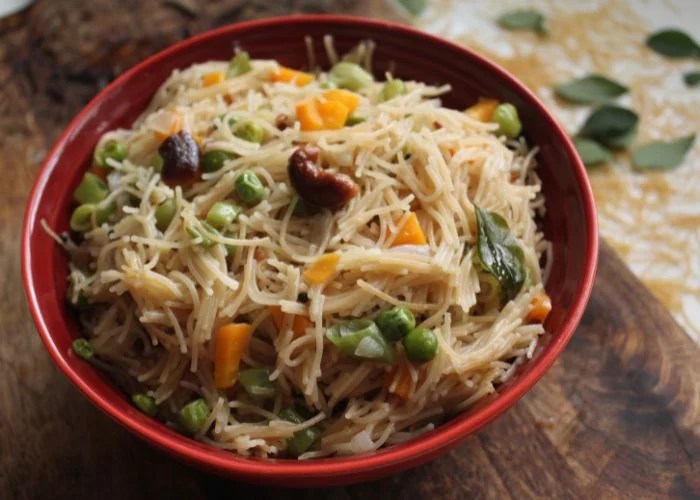semiya upma served in a red bowl with fried cashews on top
