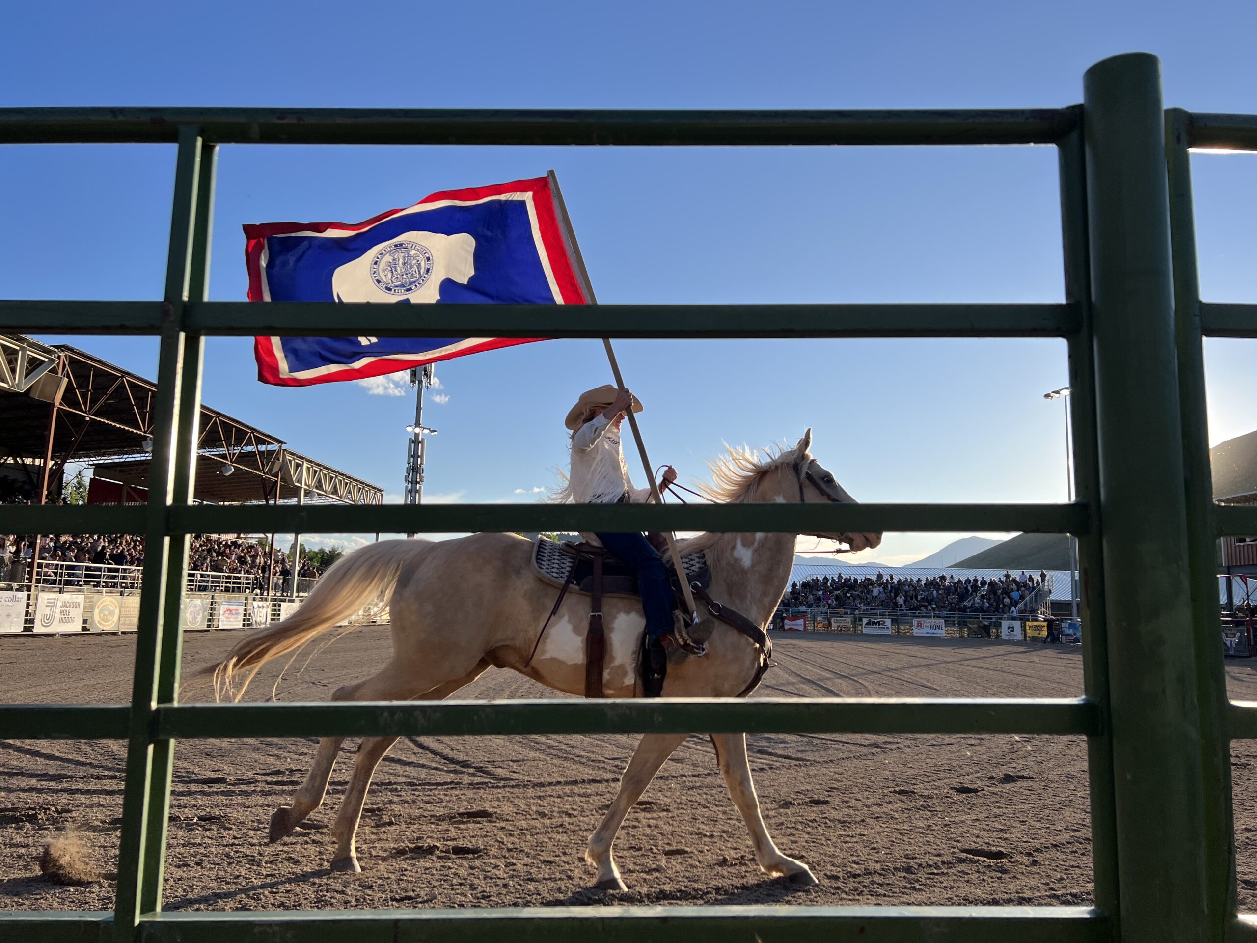 A member of the Jackson Hole Rodeo royalty carries the Wyoming flag at