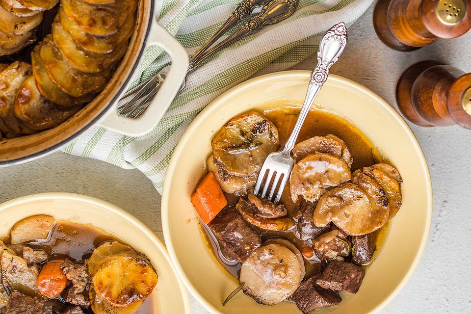 Overhead view of bowls of a beef and potato dish.