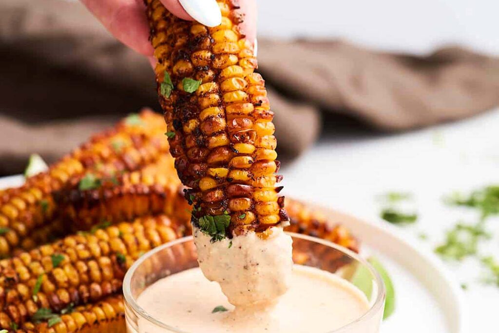 Dipping corn ribs into dip.