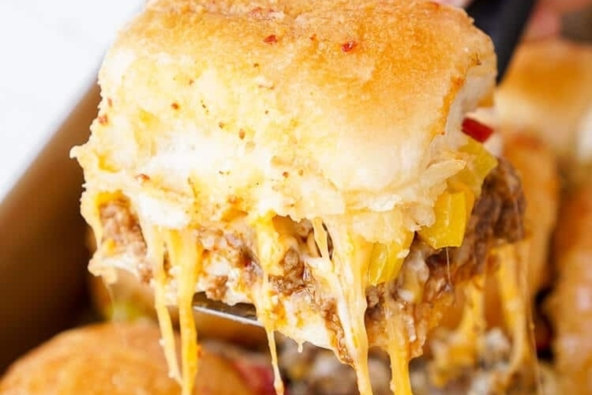 A person enjoying deliciously cheesy sliders.