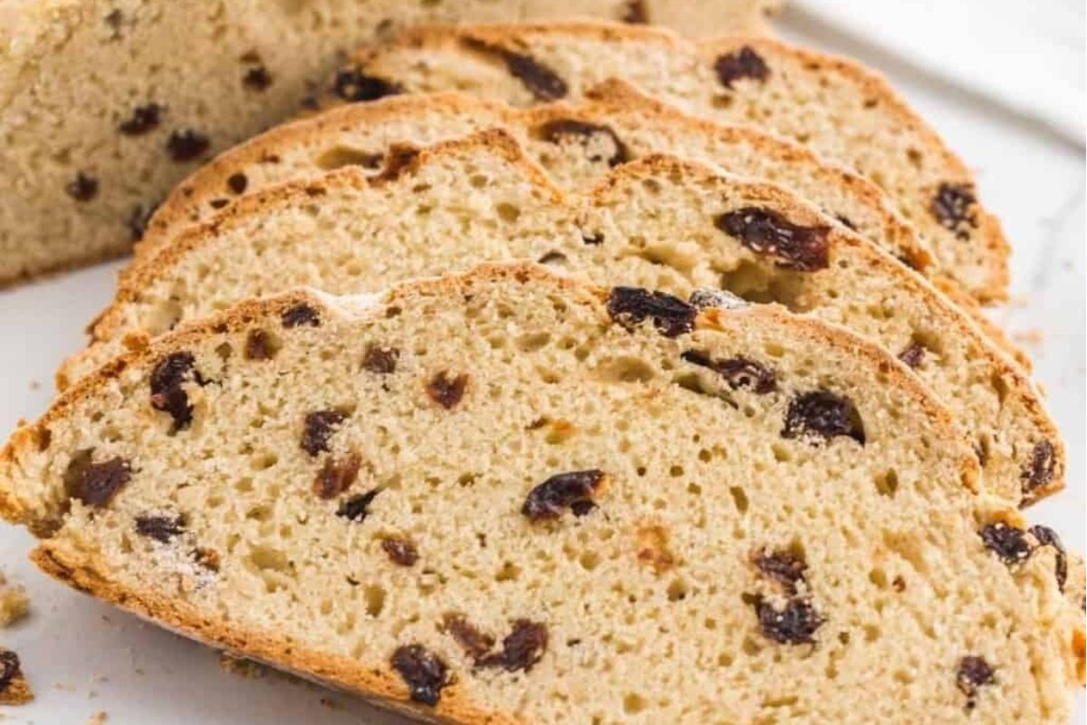 A slice of raisin bread from our bread recipes on a white plate.