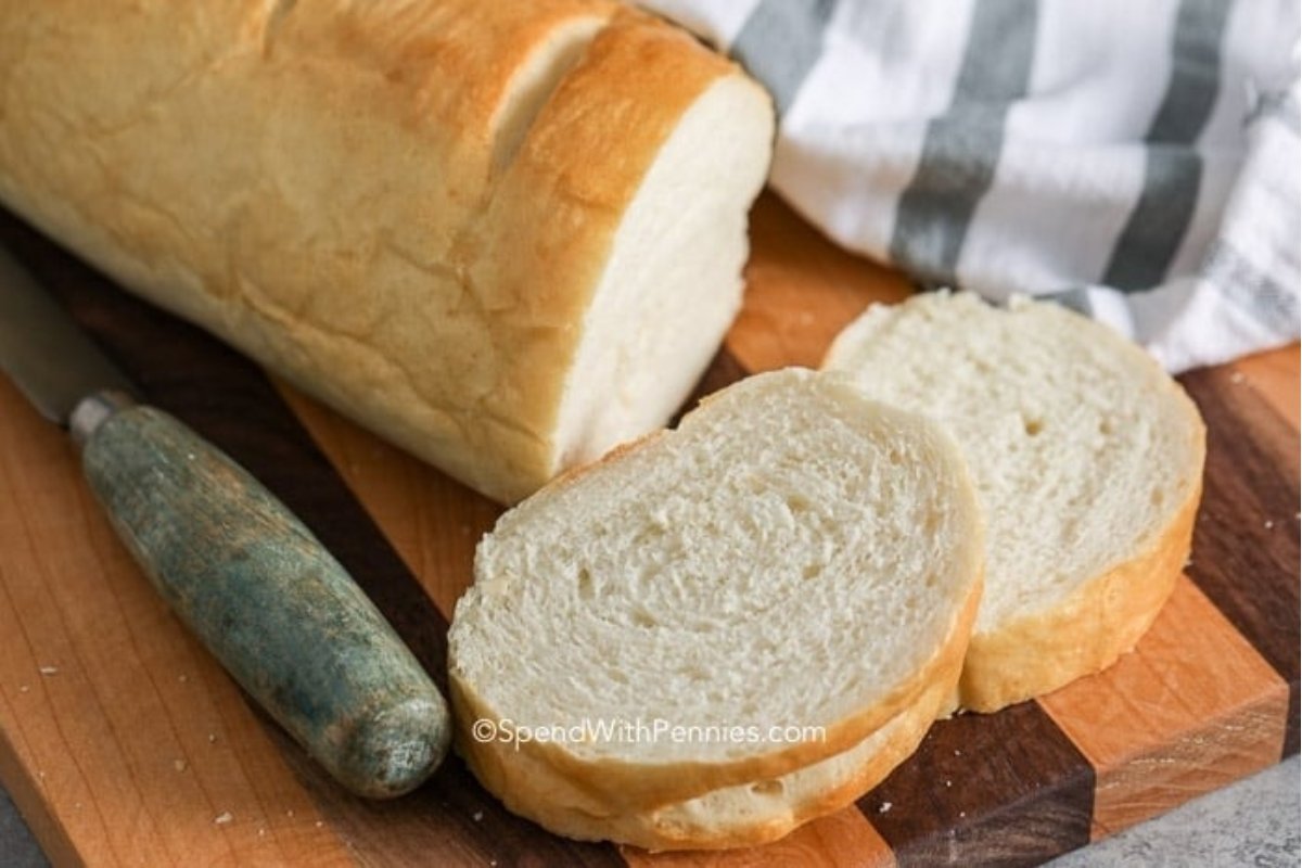 A loaf of bread on a cutting board with a knife, ready for some bread recipes.