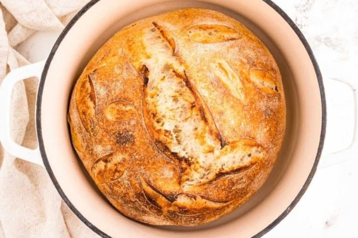 A loaf of bread, integral to many bread recipes, sits in a white bowl.