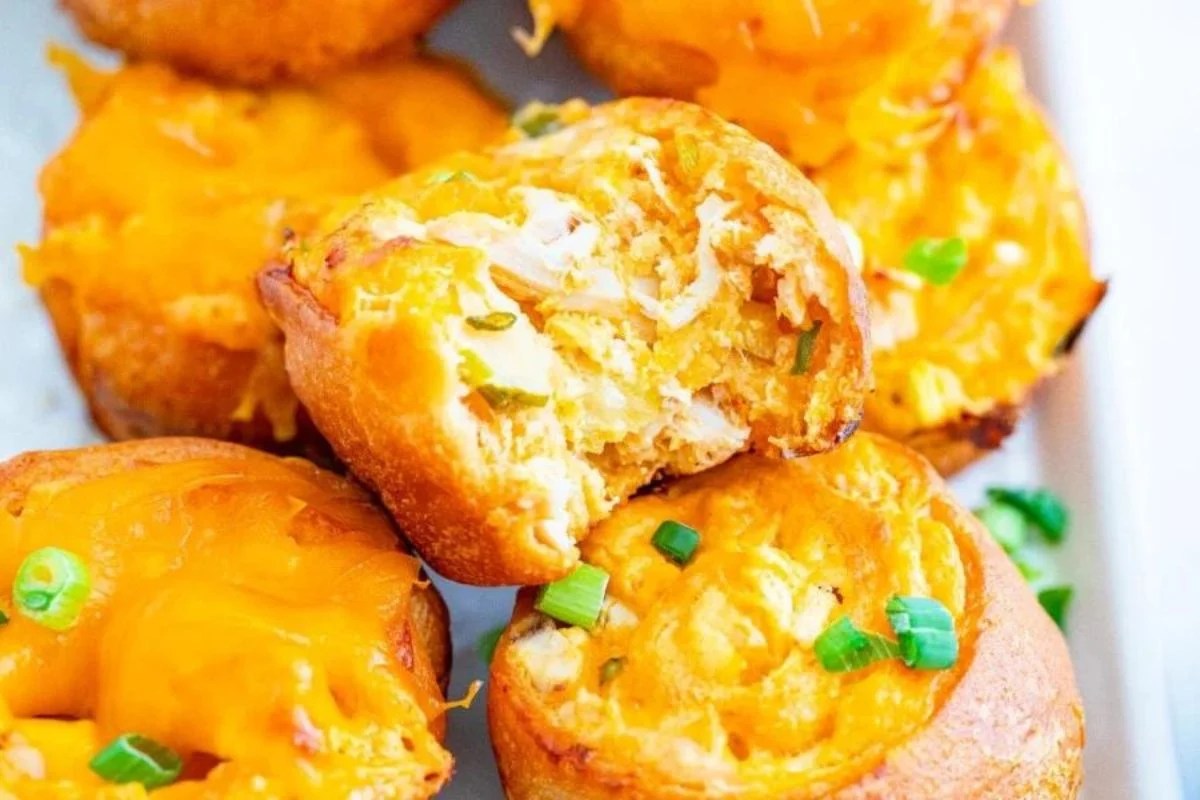 Golden-brown cheese-topped muffins garnished with chopped green onions and Buffalo chicken.