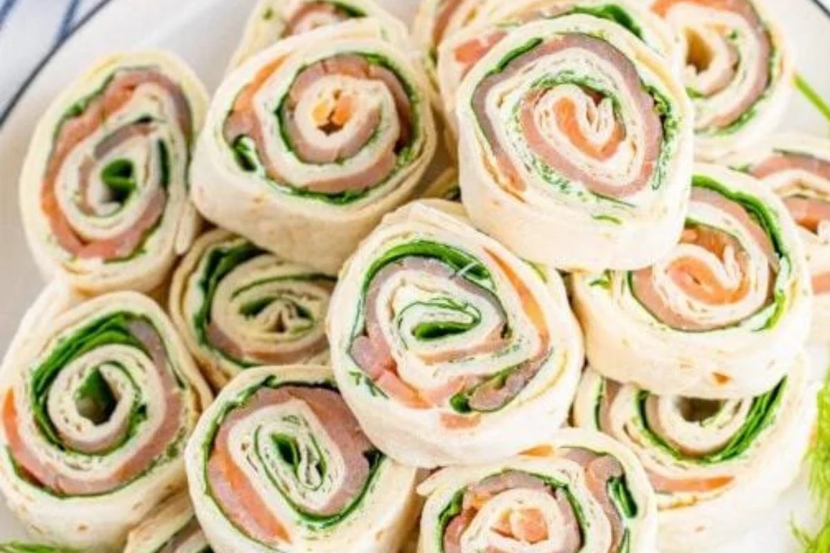 Pinwheel sandwiches with turkey, cheese, and lettuce on a plate featuring Pinwheel Recipes.