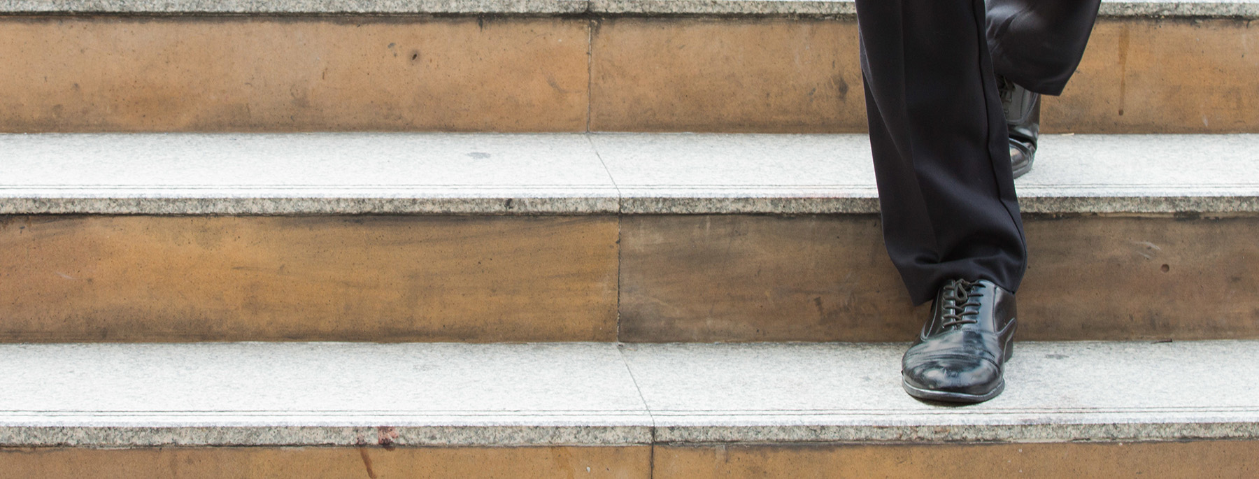 Close up of man's leather shoes while walking down the stairs in