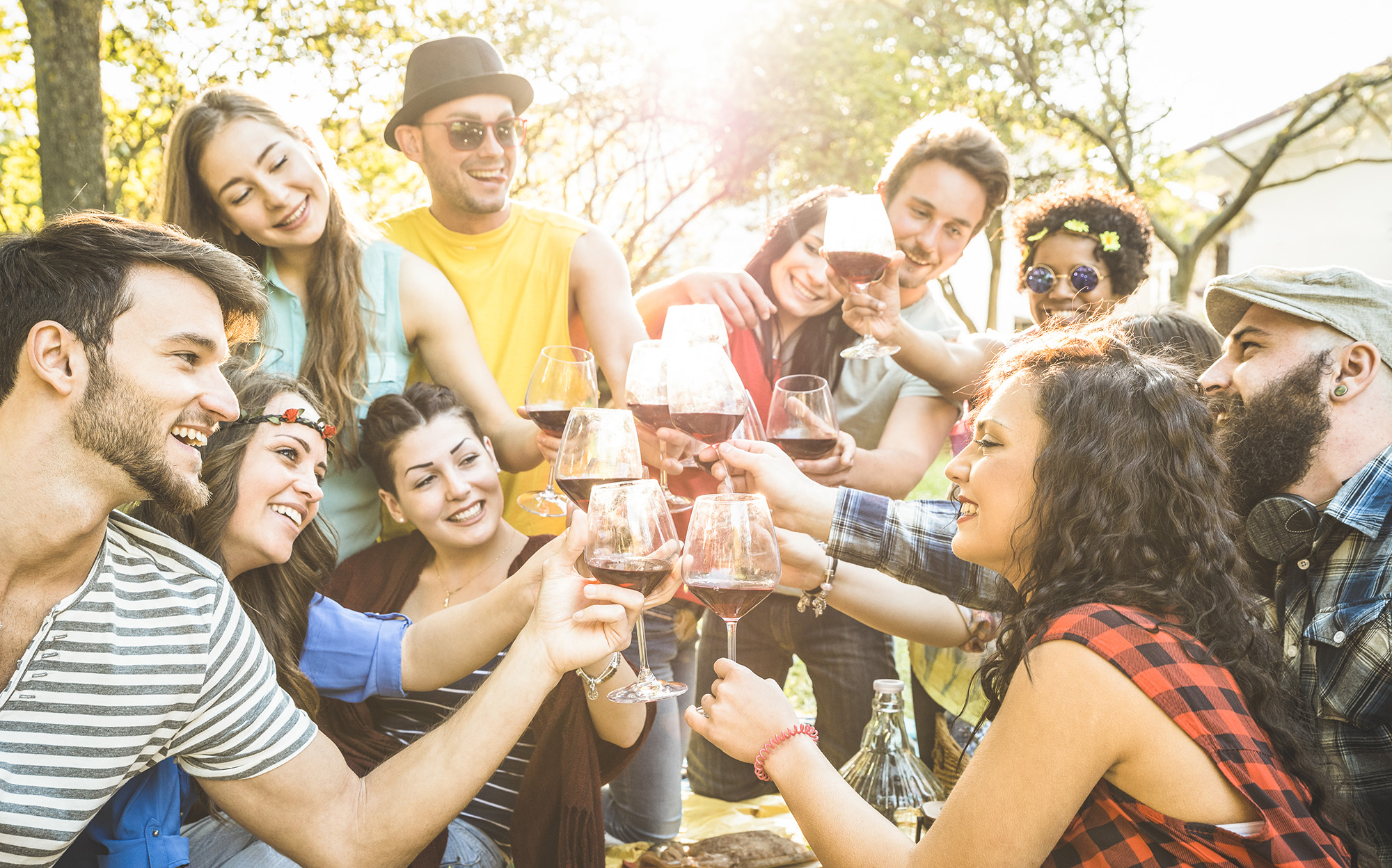 Group of friends toasting red wine having fun outdoor cheering at bbq Group of friends toasting red wine having fun outdoor cheering at bbq
